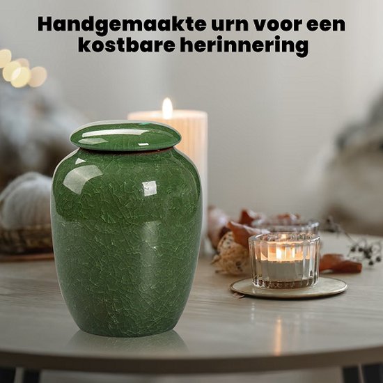 Groene keramische urn met barstenpatroon, tentoongesteld op een tafel met kaarsen.