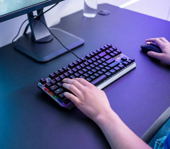 Persoon gebruikt een compact, tenkeyless gaming toetsenbord met RGB-verlichting.