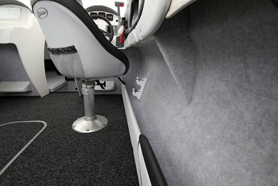 Interieur van een boot met grijs vloertapijt, grijze stoel en grijze wandbekleding.