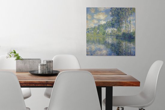 Tableau de Claude Monet: Peuples au bord de l'Epte, suspendu au-dessus d'une table à manger en bois avec des chaises blanches.