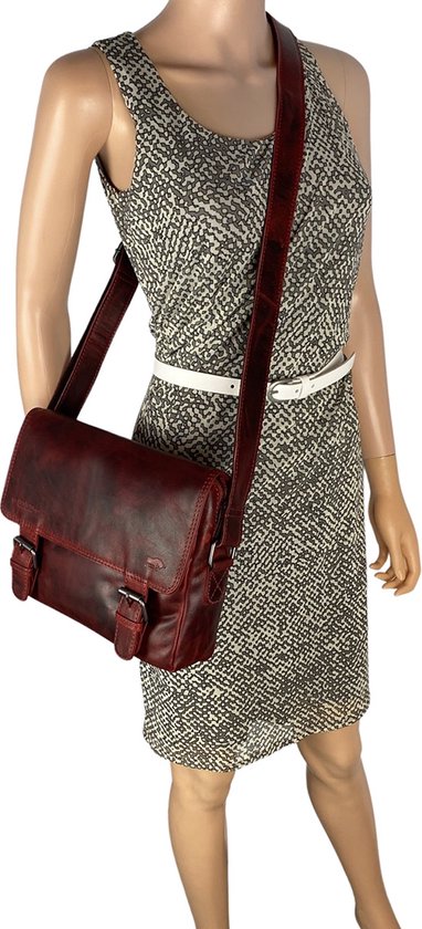 Sac bandoulière en cuir rouge porté par une mannequin avec une robe grise abstraite.