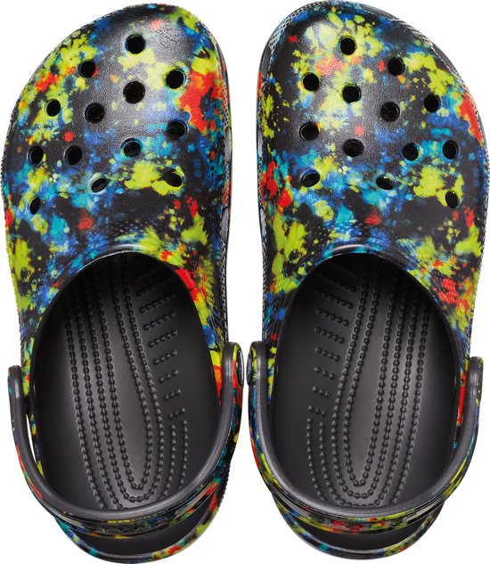 Paar zwarte Crocs met veelkleurige verfspatten, van bovenaf gezien.