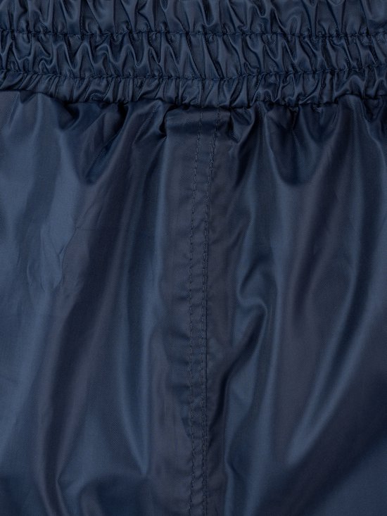 Detail van de elastische tailleband en stiksels op een donkerblauwe regenbroek.