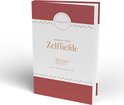 Gesloten dagboek met de titel 'DAGBOEK VOOR Zelfliefde' in goudkleurige letters. De kaft is crèmekleurig met bordeauxrode accenten, hartjes en de tekst 'Elma van Vliet'.