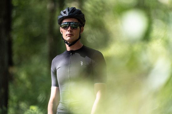 Man met zwarte fietshelm en sportbril met gespiegelde glazen, draagt zwart fietsshirt met logo.