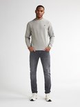 Man draagt grijze slim fit jeans, een grijze sweater en witte sneakers.