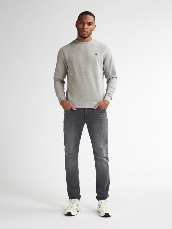 Man draagt grijze slim fit jeans, een grijze sweater en witte sneakers.