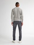 Man van achteren gezien, draagt grijze slim fit jeans en een grijze sweater.