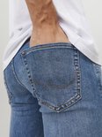 Close-up van de achterkant van een lichtblauwe jeans, met een hand in de zak.
