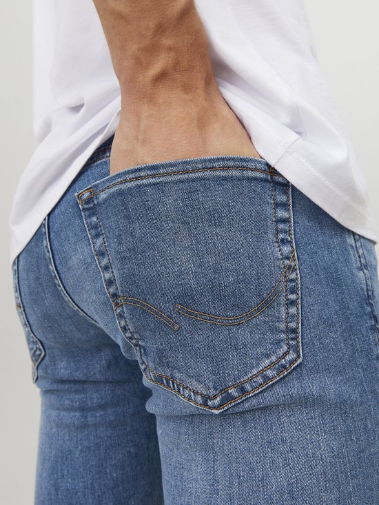 Close-up van de achterkant van een lichtblauwe jeans, met een hand in de zak.