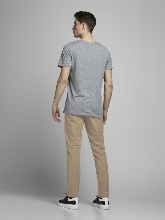 Jonge man in grijze t-shirt en beige chino broek, van achteren gezien.