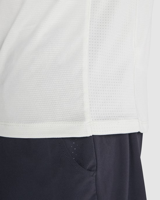 Close-up van de zoom en zijkant van een wit Roly sportshirt, met mesh-materiaal.
