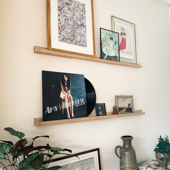 Twee lichte houten zwevende planken met lijsten, een vinylplaat en decoraties.