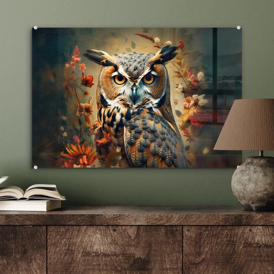 Une peinture sur verre d'un hibou aux yeux jaunes et aux plumes brunes, entouré de fleurs, accrochée au-dessus d'une commode en bois.
