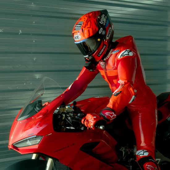 Motorcoureur in rood lederen pak en helm op een rode Ducati motor.