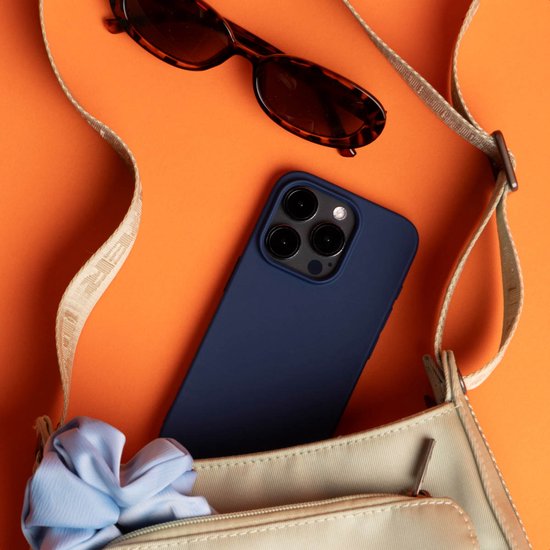 Donkerblauwe telefoon met backcover in een tas, met zonnebril en scrunchie.