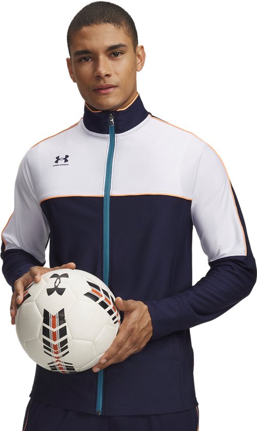 Man met voetbal in donkerblauw, wit en oranje sportvest met ritssluiting.
