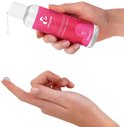 Handen houden een flesje EasyGlide aardbei glijmiddel. Een druppel glijmiddel op een vinger.