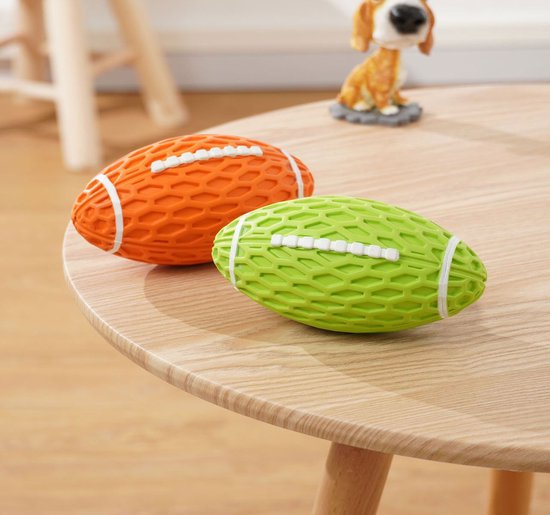 Oranje en groene rugbyballen met honingraatpatroon en witte lijnen, liggend op een houten tafel.