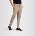 Man in beige chino broek met zwarte sneakers en zwarte T-shirt, handen in zakken.