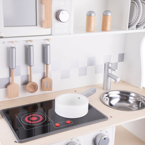 Houten speelgoedkeuken met kookplaat, aanrecht met spoelbak en zilveren kraan. Houten keukengerei hangt aan haken.
