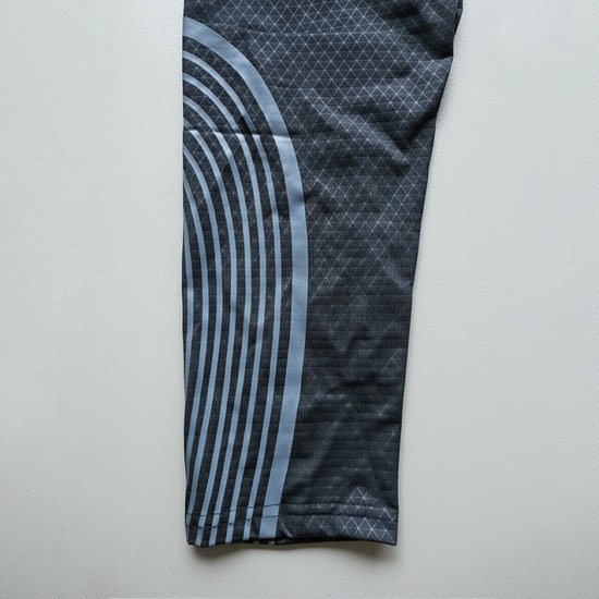 Zwarte legging met een fijn ruitpatroon, grijze lijnen aan de zijkant en lichtblauwe gebogen lijnen.