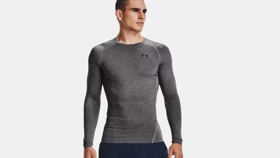 Man met grijs sportshirt met lange mouwen, ronde hals en zwarte Under Armour logo.