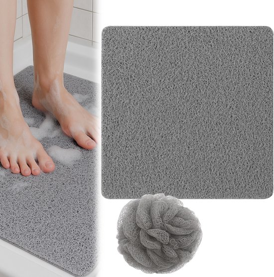 Voeten op een grijze antislipmat in een douche met zeepbellen. Naast de mat ligt een grijze netpons.