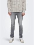 Man in grijze jeans en een beige geruit overhemd, gezien vanaf de voorkant.