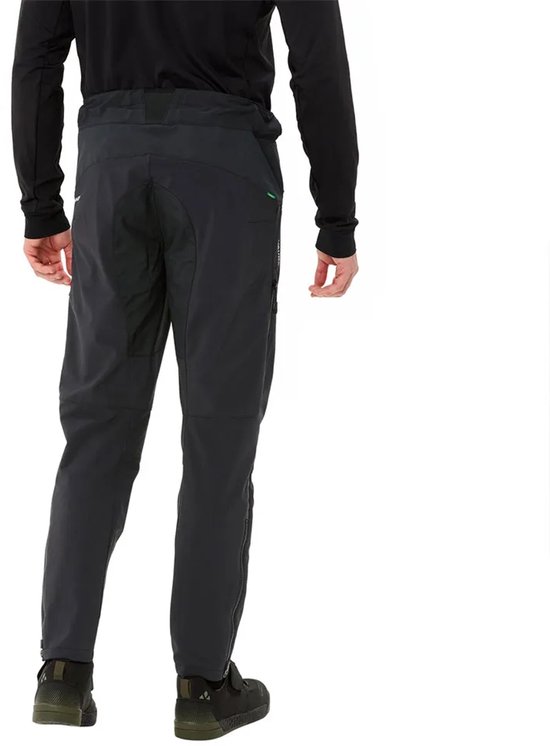 Man in zwarte softshell fietsbroek, achterkant, met ritsen op de kuiten en groene accenten.
