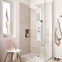 Wit douchepaneel met regendouche, waterval, handdouche en massagejets in een lichte badkamer met lichte tegels.
