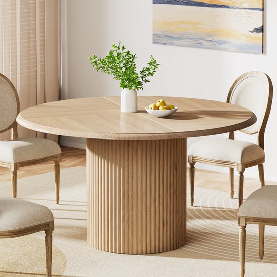 Ronde, uitschuifbare eettafel met houten visgraatblad en gecanneleerde poot, aan weerszijden omringd door stoelen.