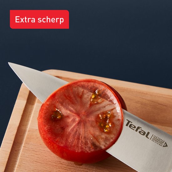 Close-up van een Tefal mes dat een tomaat snijdt
