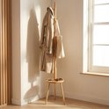 Houten kapstok met trenchcoat, tas, en zonnebril op het plateau. In een lichte kamer.