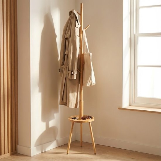 Houten kapstok met trenchcoat, tas, en zonnebril op het plateau. In een lichte kamer.