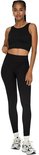 Model met gevlochten haar, draagt zwart sport-set met crop top en nauwsluitende legging met hoge taille en geribd patroon.