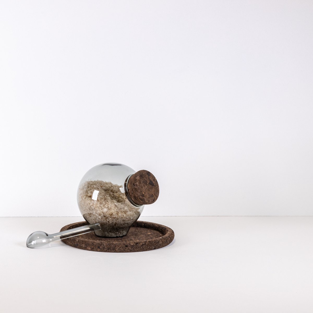 Zoutpotje van grijs rookglas met kurken stop, glazen lepeltje en kurk onderzetter – design zoutpot – rookglas zout potje – ontwerp Maarten Baptist
