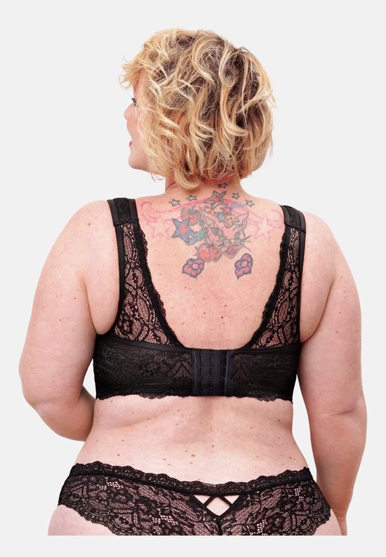 Model met blonde krullen en tatoeages op de rug, draagt een zwarte kanten bralette.