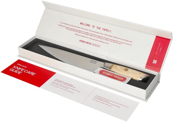 Een Shinrai Knives koksmes met houten handvat in een witte doos, met een rode handleiding voor mesonderhoud.