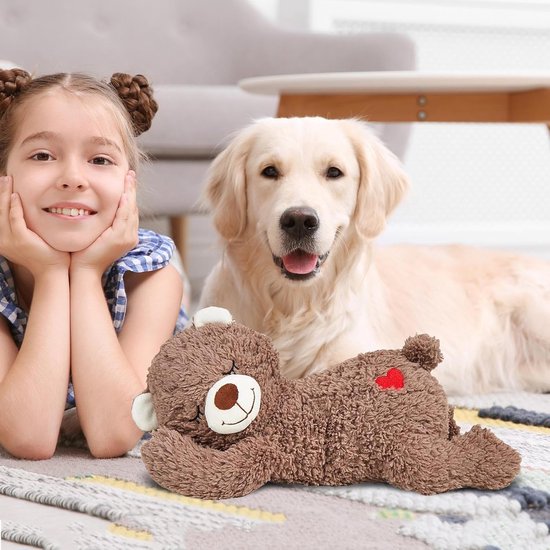 Bruine pluche beer met rode hart op rug, naast een jong meisje met hondenoren en een golden retriever.