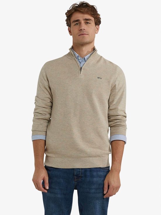Beige trui met 'MCG' logo, ritssluiting en donkerblauwe kraag.