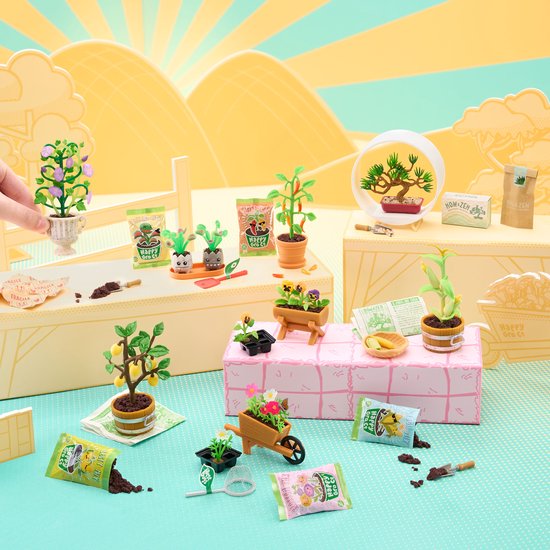 Miniatuur tuin scène met verschillende plantjes in potjes, een kruiwagen, gieter en zakjes potgrond.