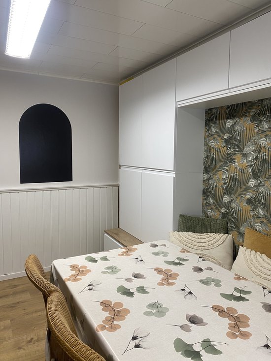 Tableau noir en forme d'arche sur un mur, au-dessus d'une table avec des chaises.