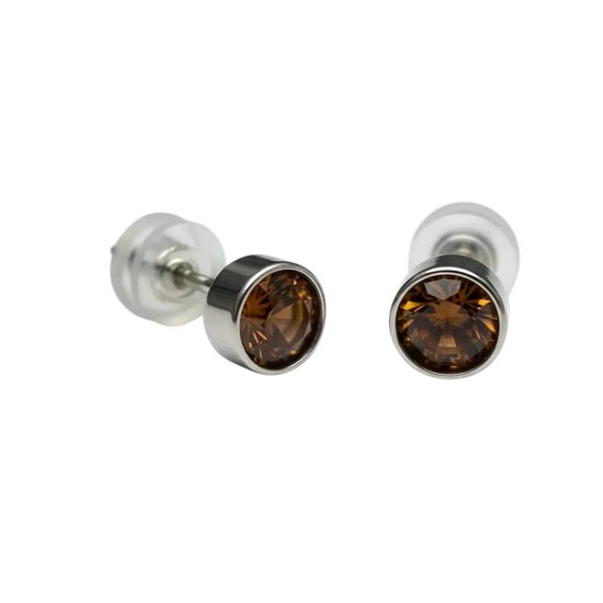 Deux clous d'oreilles avec des cristaux ronds marron facettés dans un sertissage argenté.