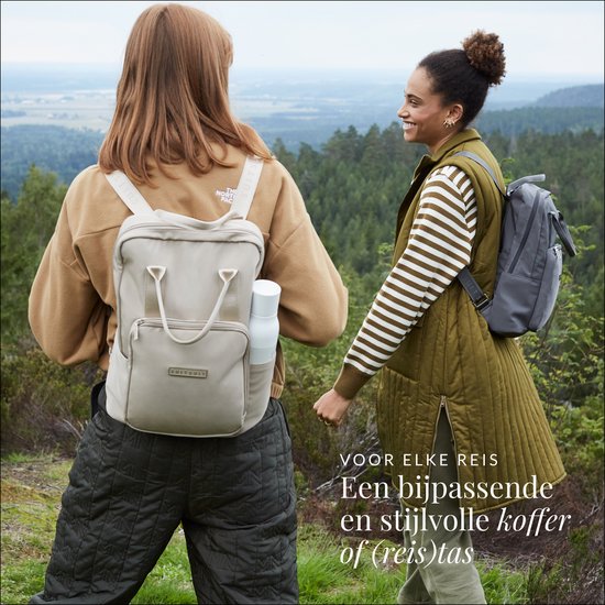 Twee vrouwen met rugzakken in een bosrijke omgeving. Tekst "Voor elke reis Een bijpassende en stijlvolle koffer of (reis)tas"