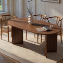 Ovale eettafel van donker hout met vier houten stoelen met rotan zitting.