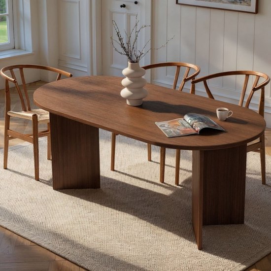 Ovale eettafel van donker hout met vier houten stoelen met rotan zitting.