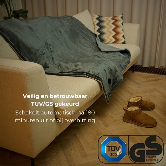 Grijze elektrische deken op een bank, met TUV/GS keurmerk. Veilig en betrouwbaar, schakelt automatisch uit na 180 minuten.