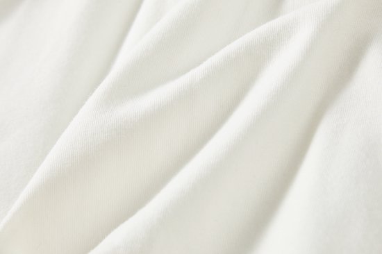 Detail van de off-white stof van de rok met zachte plooien.