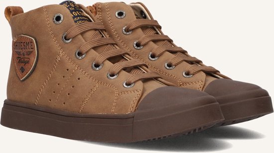 Close-up van twee bruine leren hoge sneakers, met veters, rubberen neus en zool. Met logo-embleem op de zijkant.